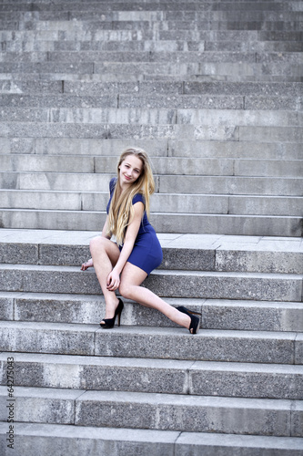 Woman in blue dress sitting on the stone steps © Andrey_Arkusha