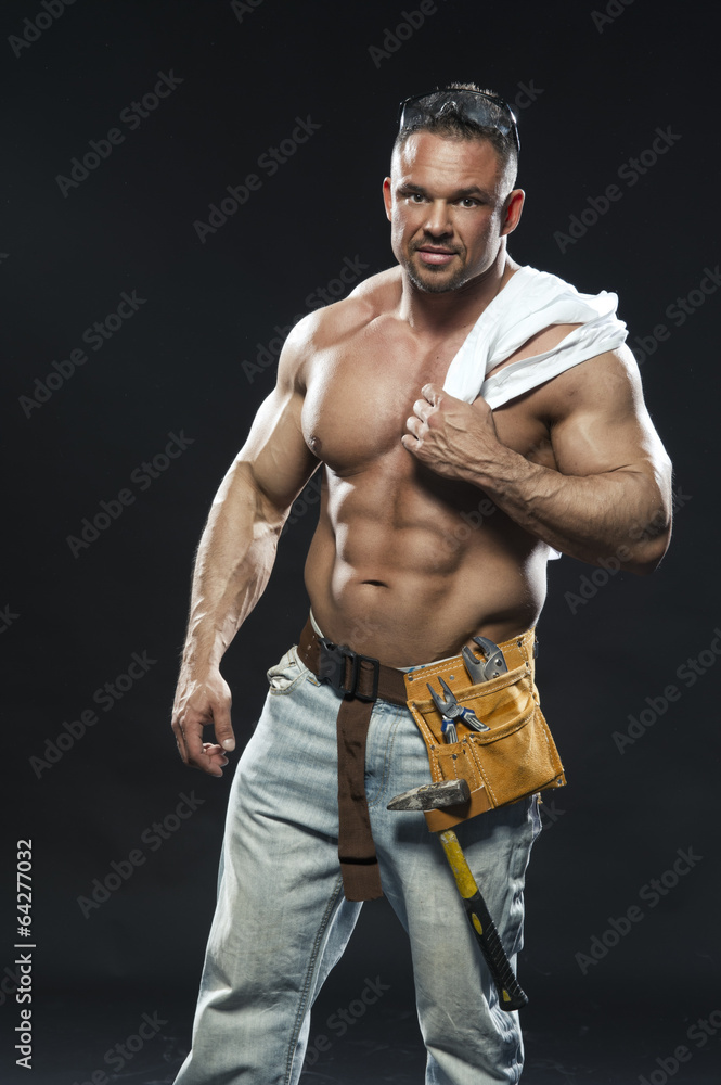 Image of young handsome builder posing, on dark background Image of young handsome builder posing, on dark background