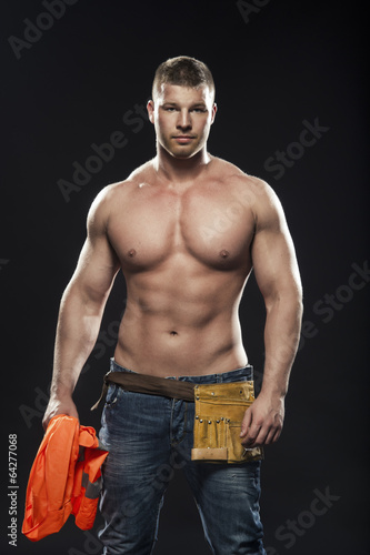 Image of young handsome builder posing, on dark background