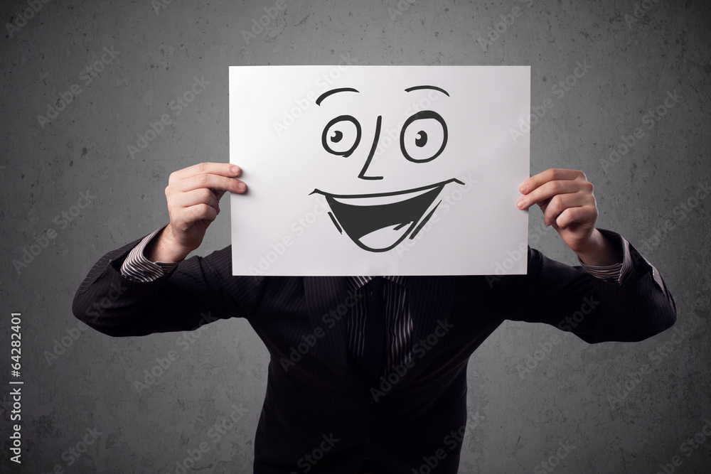 Businessman holding a cardboard with smiley face on it in front Businessman holding a cardboard with smiley face on it in front