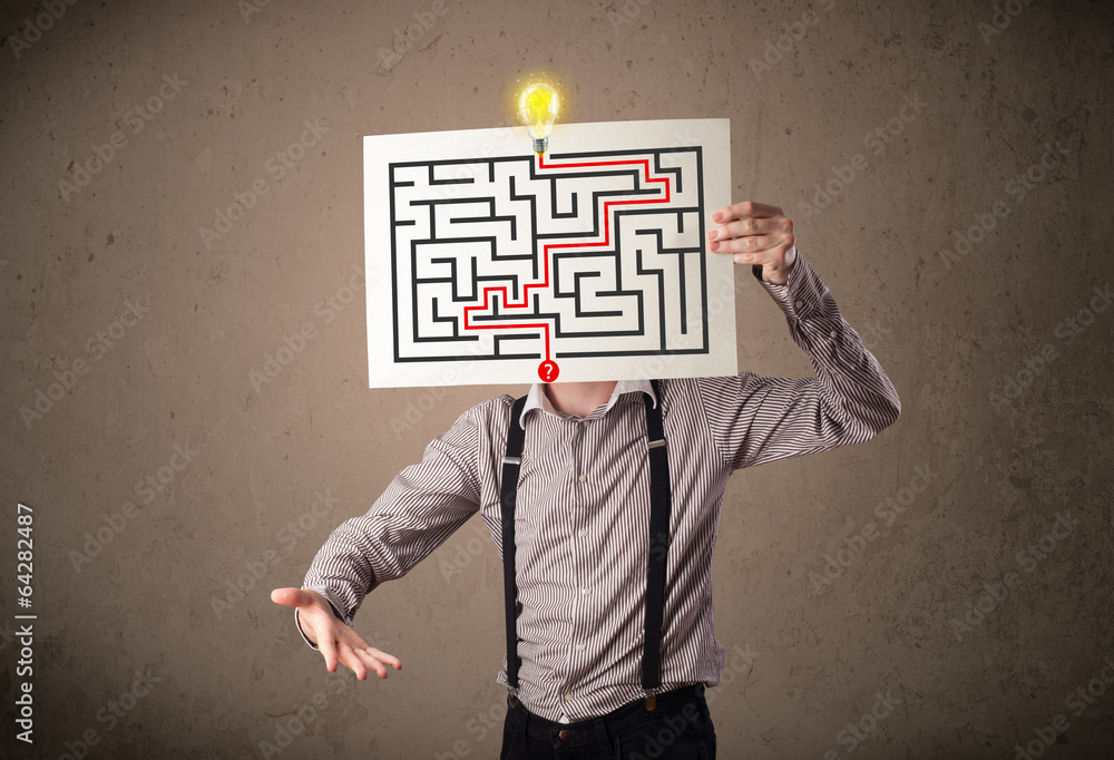Businessman holding a paper with a labyrinth on it in front of h Businessman holding a paper with a labyrinth on it in front of h