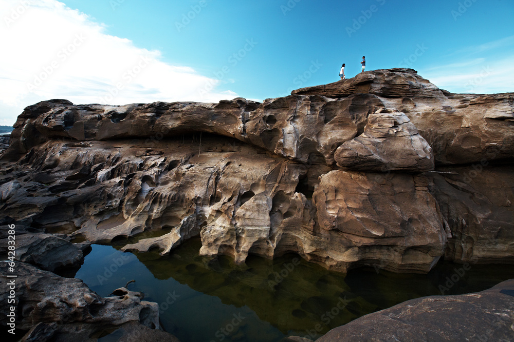 woman and boy stand on huge rock in thailand