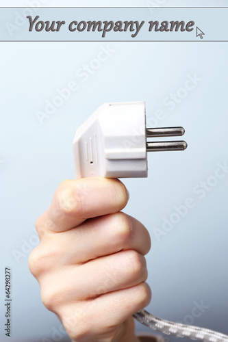 Hand holding electric plug on blue background