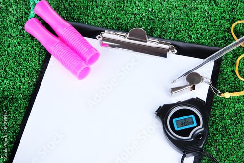 Sheet of paper and sports equipment on grass close-up