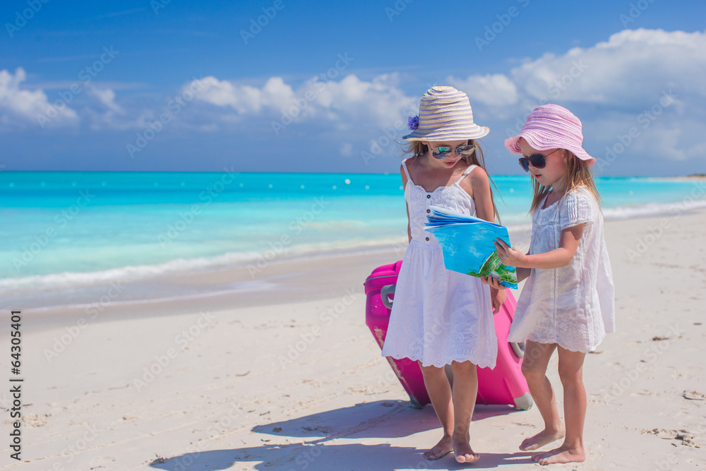Little lovely girls with big suitcase and a map on tropical Little lovely girls with big suitcase and a map on tropical