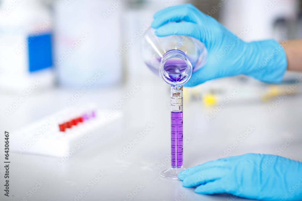 Foto Decanting a violet liquid into a graduated cylinder