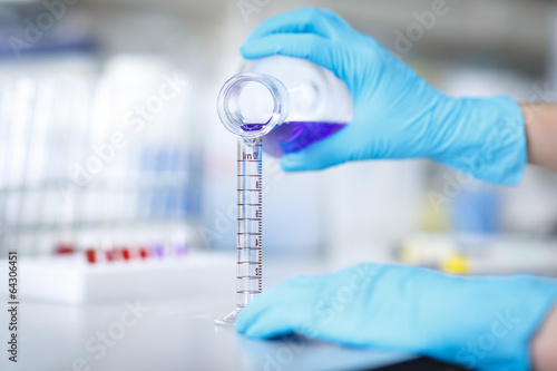 Decanting a violet liquid into a graduated cylinder