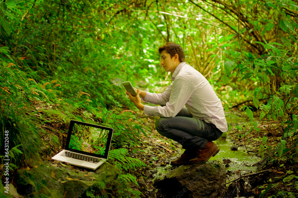 Fototapeta premium man using tablet and personal computer in the jungle