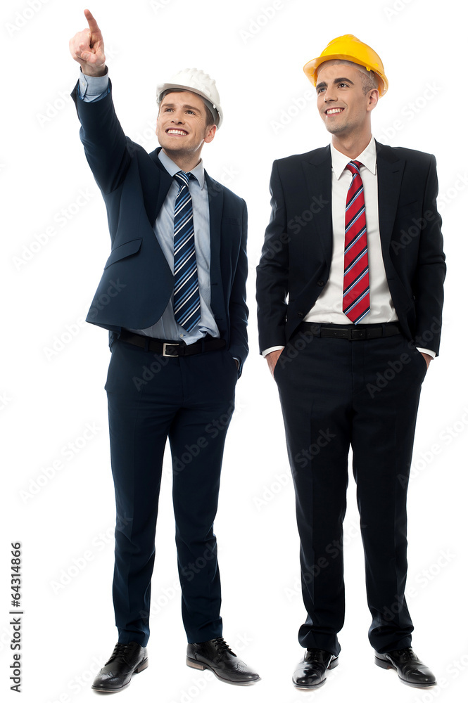 Two men in hard hats looking away Two men in hard hats looking away