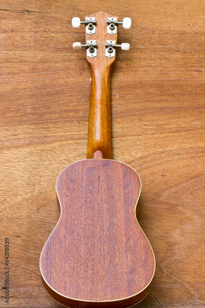 Naklejka premium The ukulele is placed on a wooden floor.