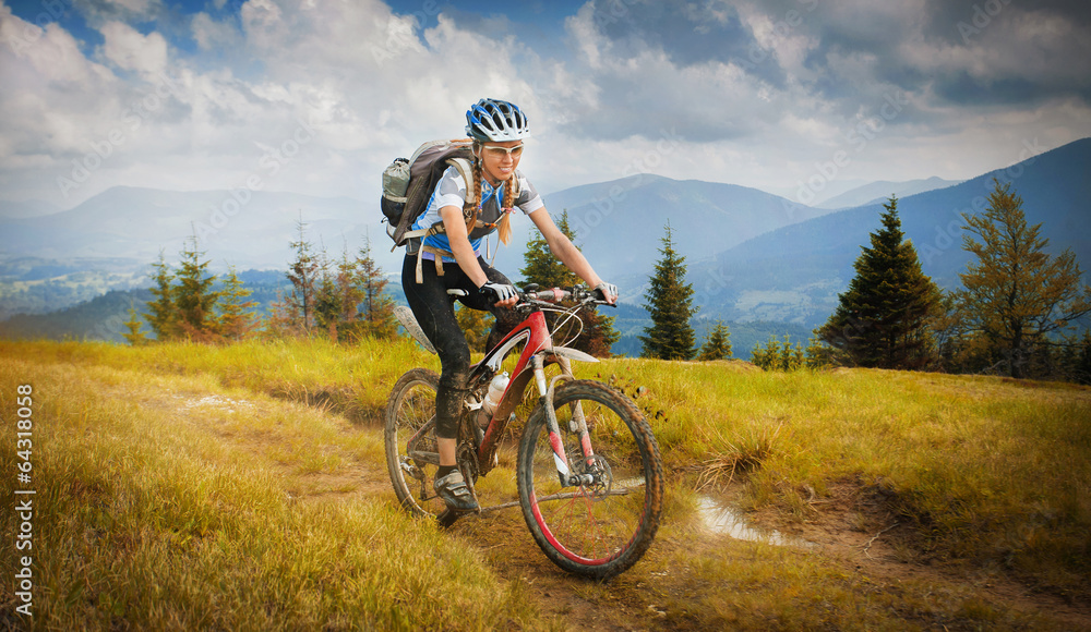 Woman mountain-bike riding on ridge with Carpatian Mountains