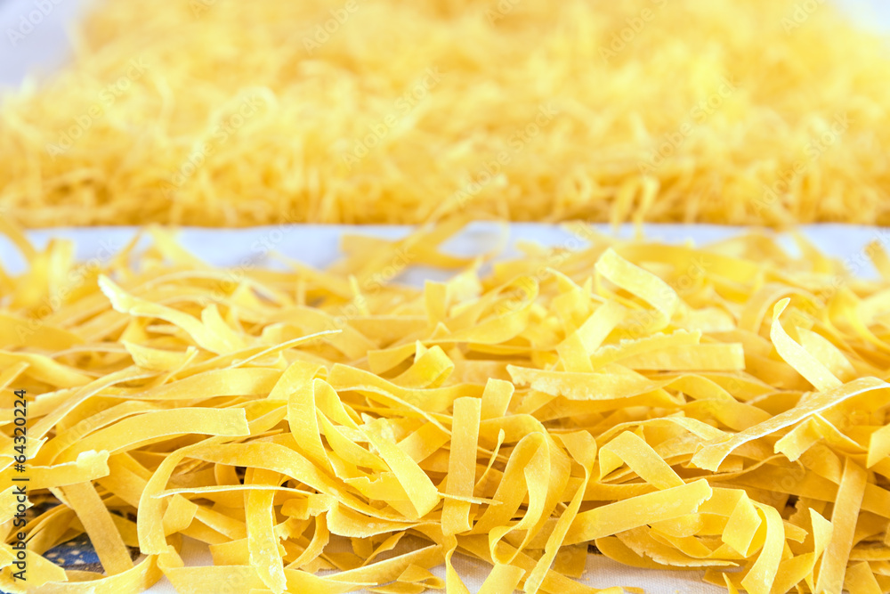 Raw pasta strewn on table for drying Raw pasta strewn on table for drying