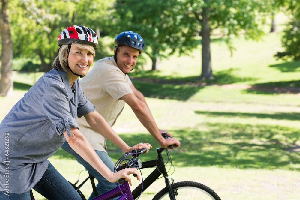 Smiling couple riding bicycles in park Smiling couple riding bicycles in park