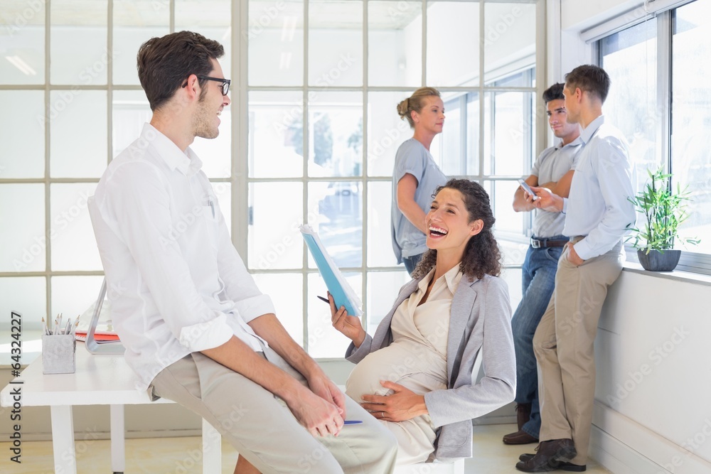 Pregnant businesswoman laughing with colleague Pregnant businesswoman laughing with colleague