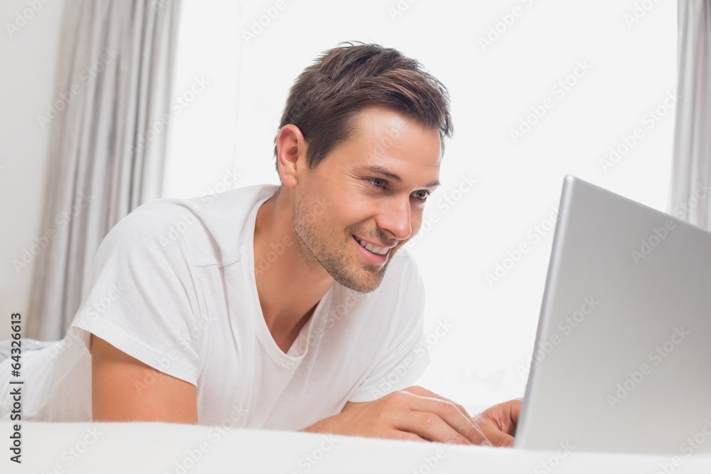 Relaxed casual man using laptop in bed Relaxed casual man using laptop in bed