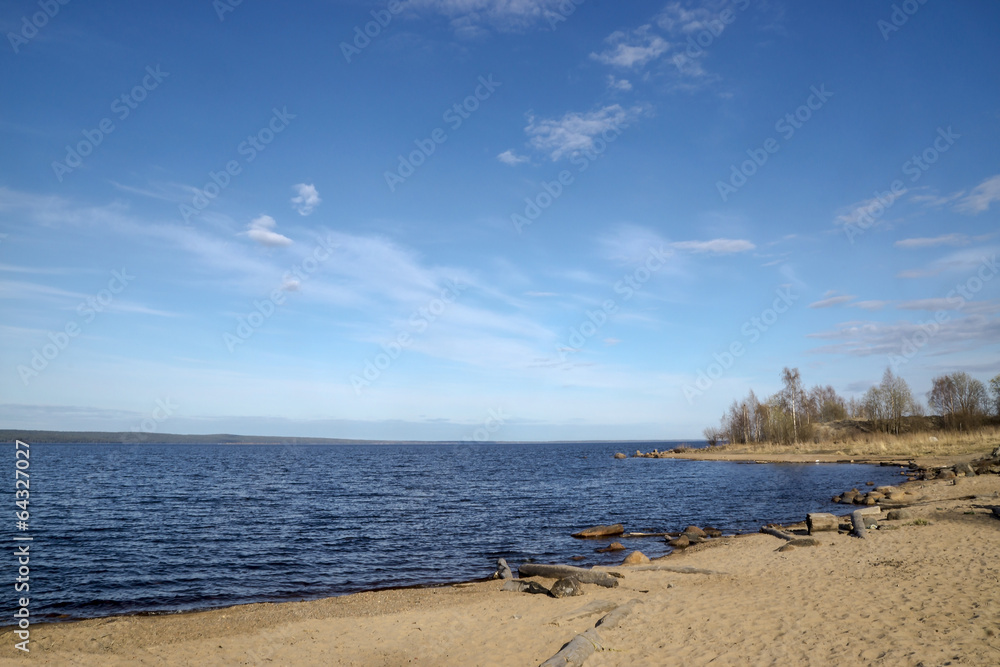 Sandy beach on lake in sunny spring day