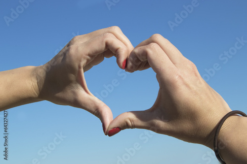 Showing heart sign with hands (sky in the background - love)