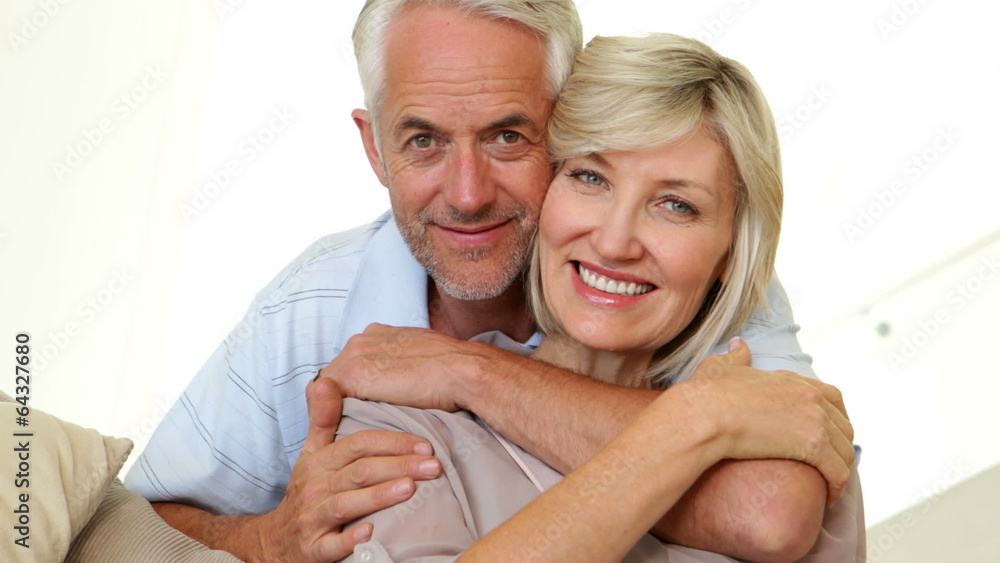 Couple hugging on the couch and smiling at camera Couple hugging on the couch and smiling at camera
