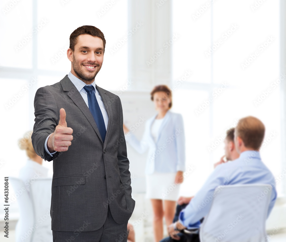 handsome buisnessman showing thumbs up in office handsome buisnessman showing thumbs up in office