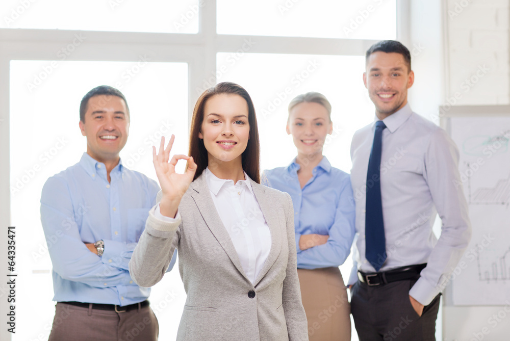 smiling businesswoman showing ok-sign in office smiling businesswoman showing ok-sign in office
