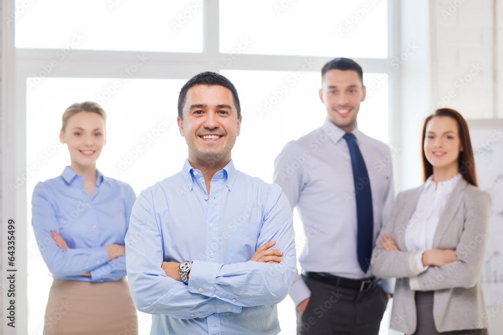 smiling businessman in office with team on back smiling businessman in office with team on back