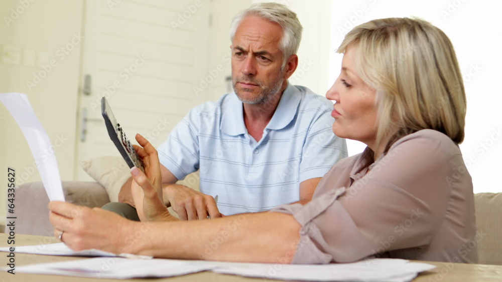 Stressed couple working out their finances on the couch Stressed couple working out their finances on the couch