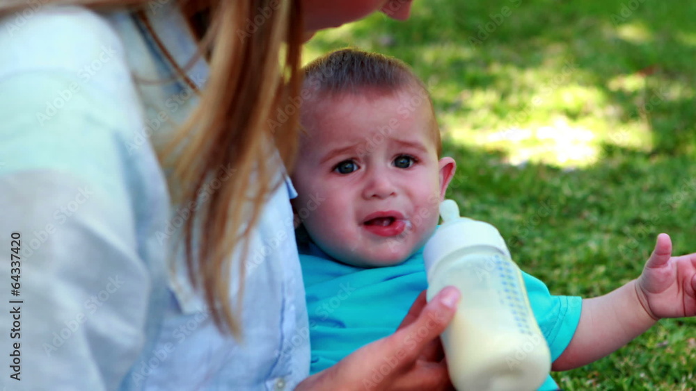 Mother feeding her cute baby son his bottle Mother feeding her cute baby son his bottle