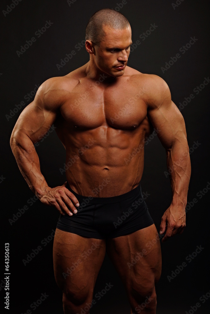 Handsome muscular man poses on gray background