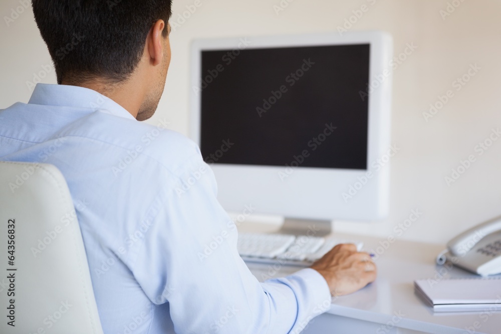 Casual businessman using computer at his desk Casual businessman using computer at his desk