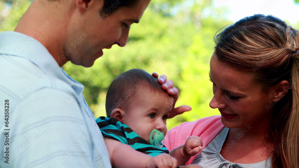 Proud parents holding baby son in the park Proud parents holding baby son in the park