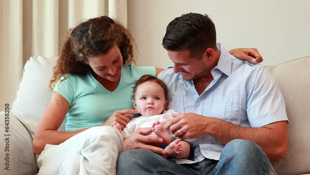 Young parents sitting on the couch with their baby son Young parents sitting on the couch with their baby son