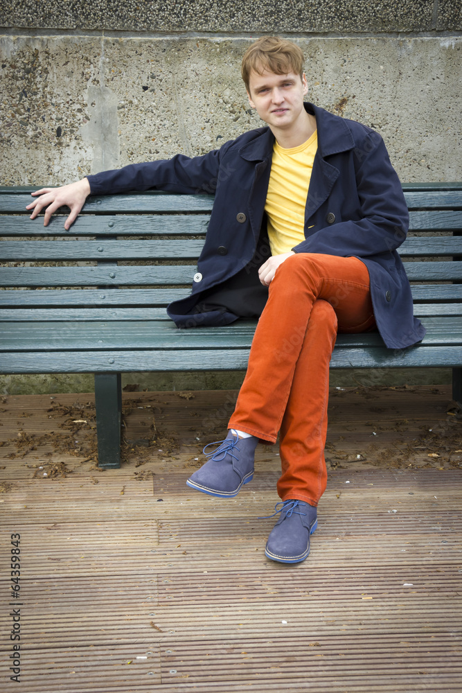 Handsome young man sitting on a bench. Candid. Handsome young man sitting on a bench. Candid.
