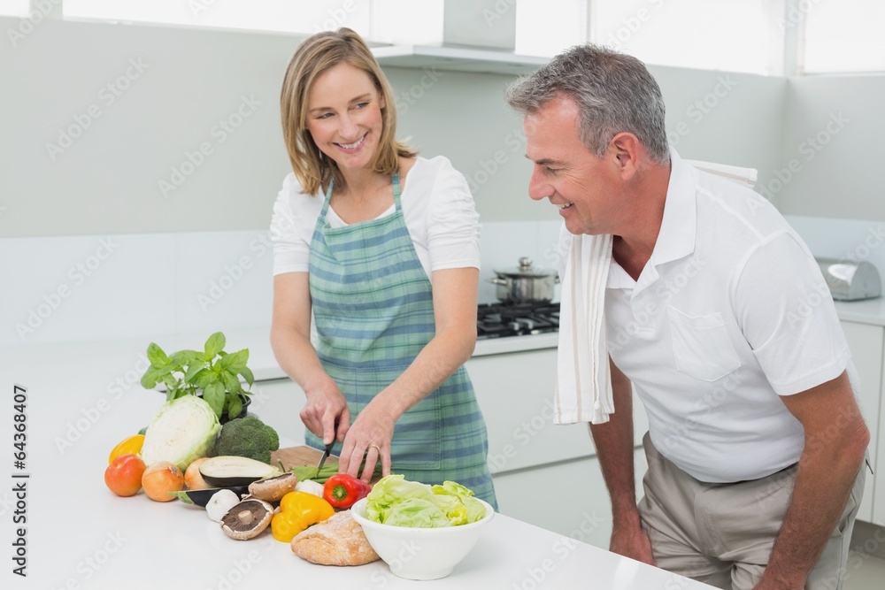 Happy couple preparing food together in kitchen Happy couple preparing food together in kitchen