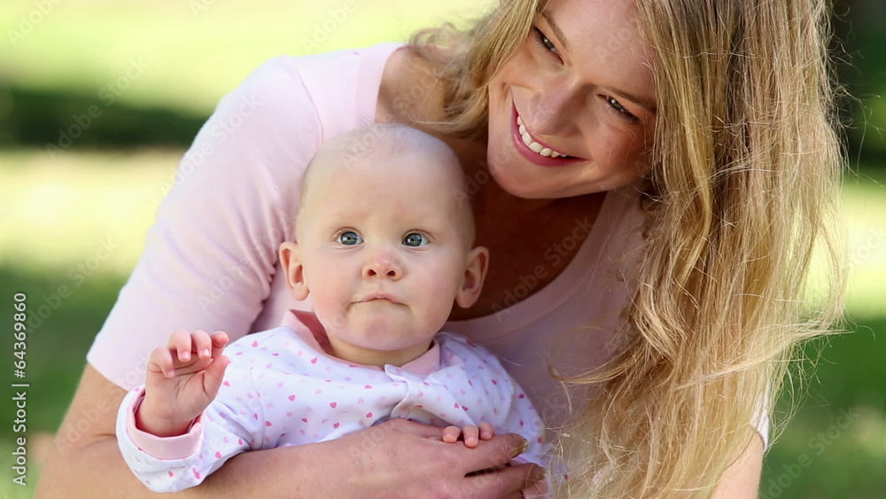 Happy mother holding her baby girl in the park Happy mother holding her baby girl in the park