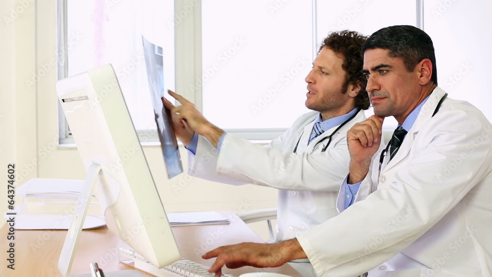 Doctors sitting at desk talking about xray Doctors sitting at desk talking about xray