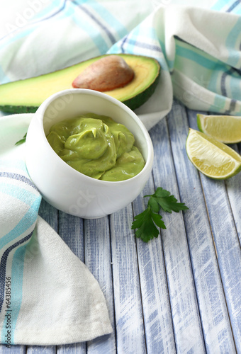 Fresh guacamole in bowl on wooden table