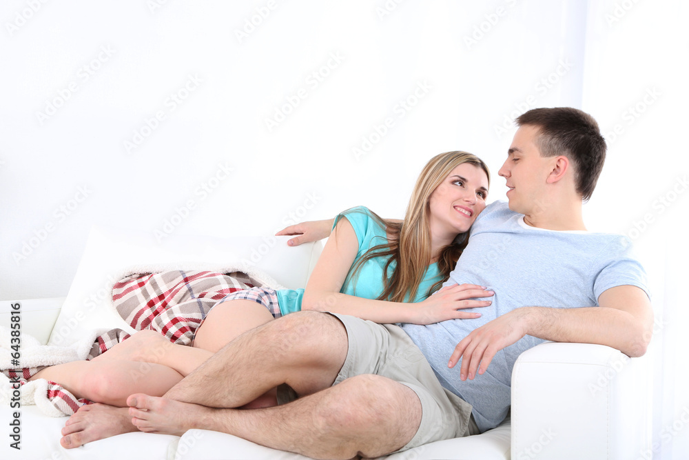 Loving couple sitting on sofa, on home interior background