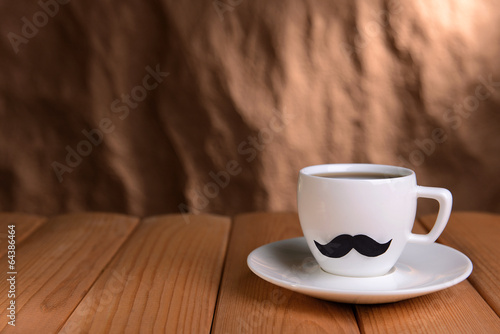 Cup with mustache on table on brown background