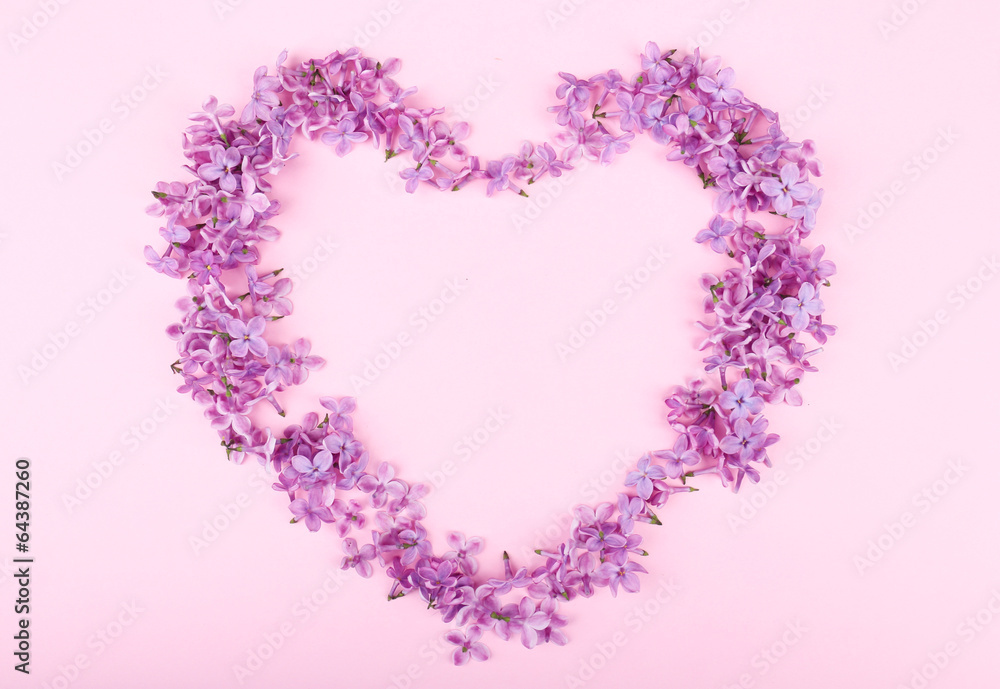 Beautiful lilac flowers in shape of heart on pink background