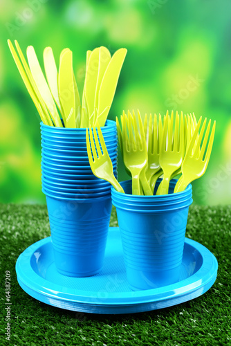 Bright plastic tableware on grass close-up