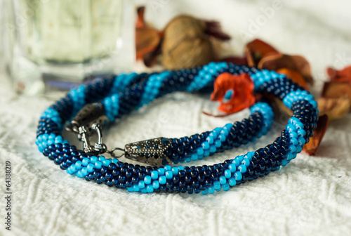 Necklace from blue beads on a textile background
