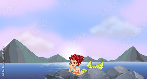 A young mermaid near the rocks at the seaside