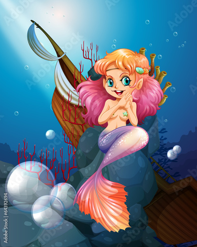 A pretty mermaid under the sea near the rocks