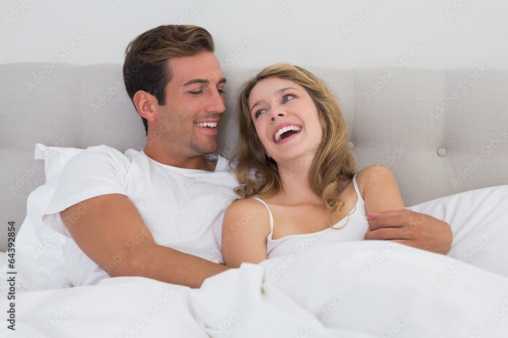 Cheerful relaxed couple sitting in bed