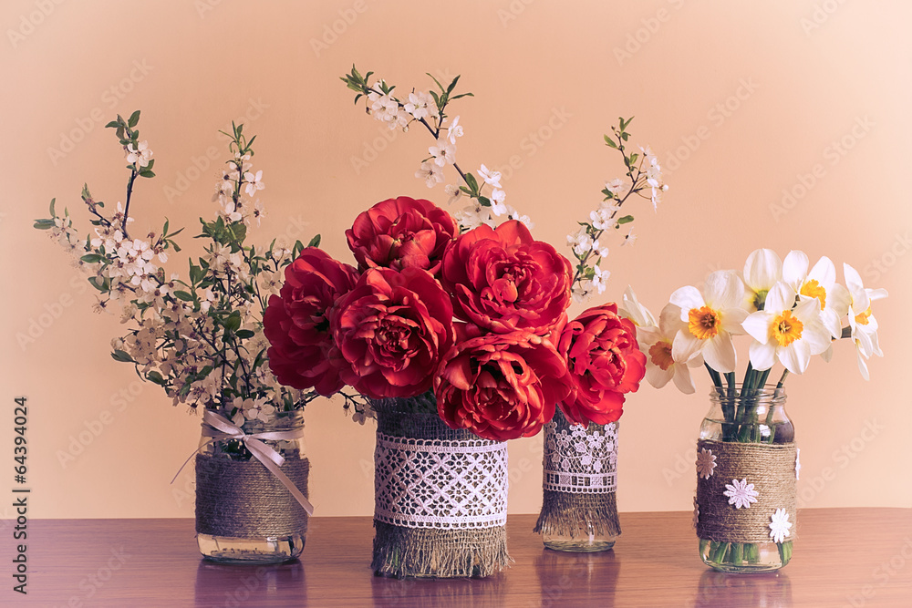 Obraz premium Spring flowers in decorated glass jars