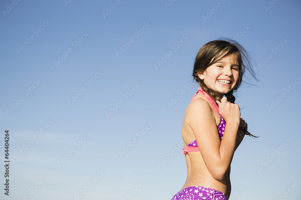 A young child in a bikini with plaited hair. Stock Photo | Adobe Stock