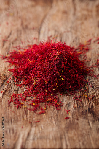 saffron spice in pile on old wooden background, closeup