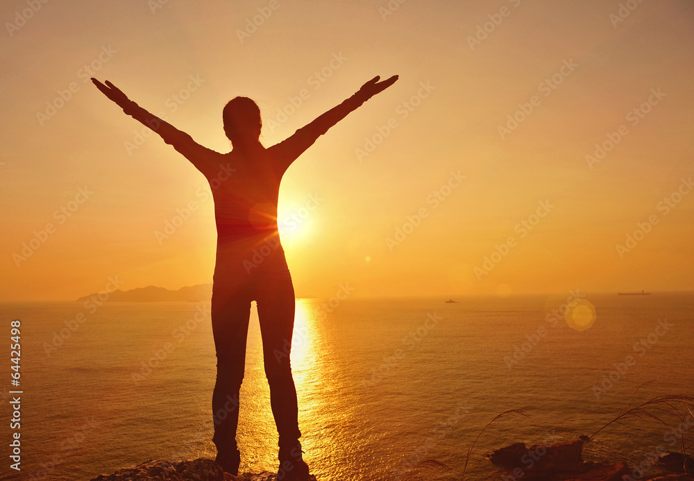 cheering woman open arms at sunrise seaside mountain peak