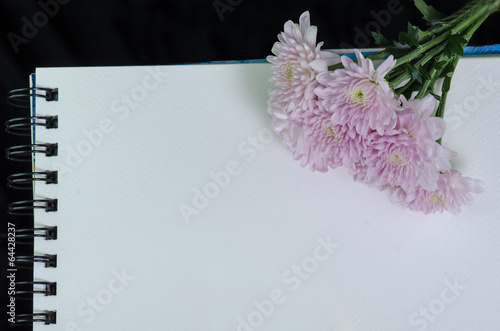 A white sketchbook, had and pink flower on black cloth photo
