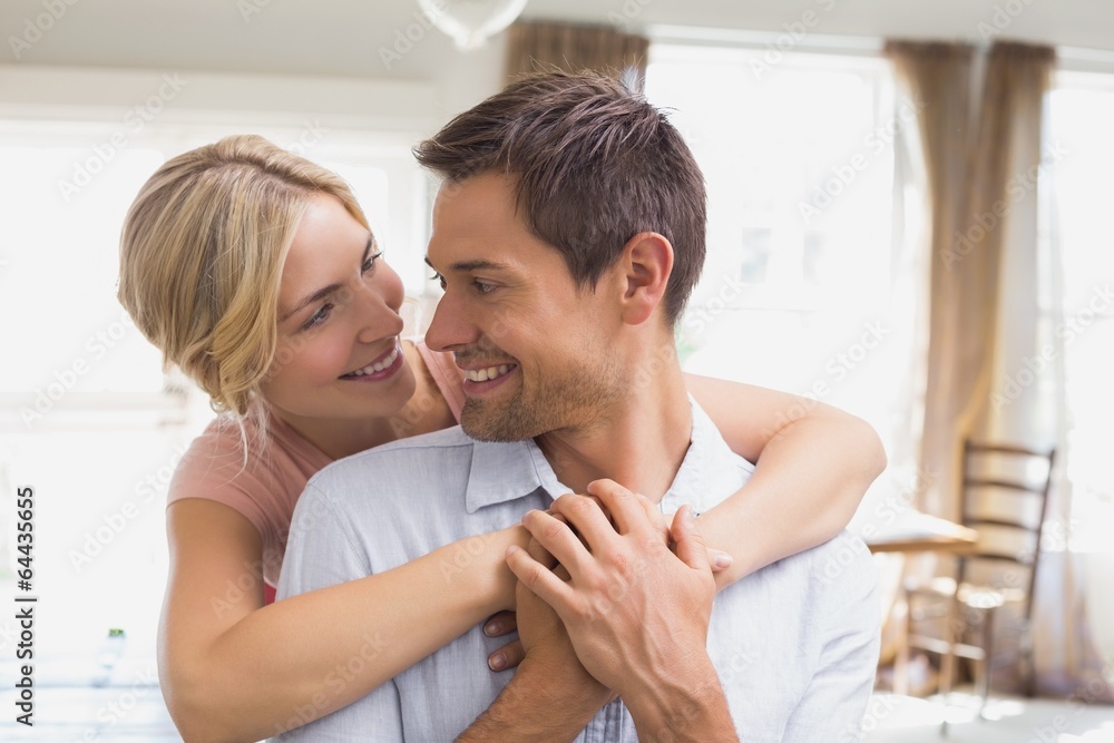 Woman embracing man from behind at home Woman embracing man from behind at home